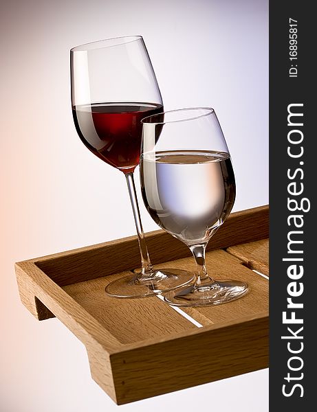 Glasses of red wine and water on wooden tray