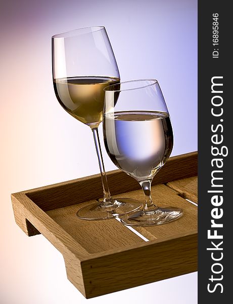 Glasses of white wine and water on a wooden tray