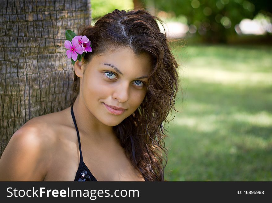 Beautiful girl with a flower under a palm