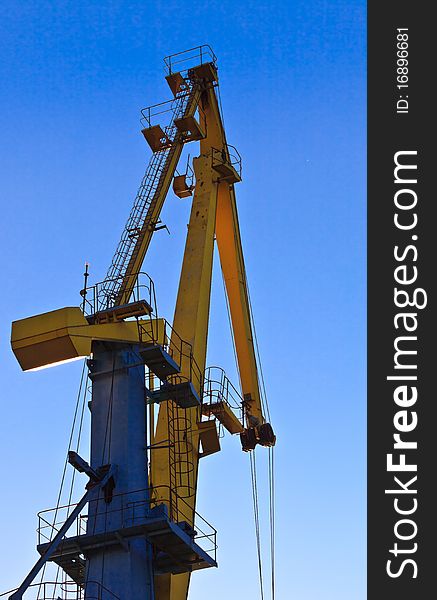 Yellow nautical crane on the blue sky. Yellow nautical crane on the blue sky