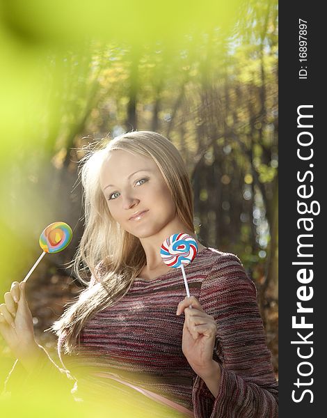 Young beautiful woman eating candy lollipops. Blurred background.