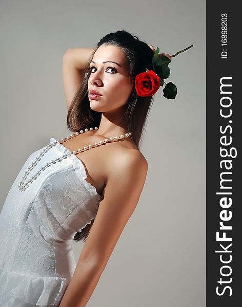 Young woman in a white dress holding a red rose