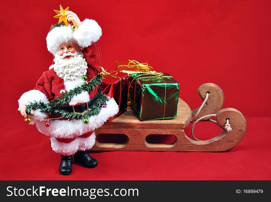 Santa trimming tree and sleigh with presents on red background. Santa trimming tree and sleigh with presents on red background