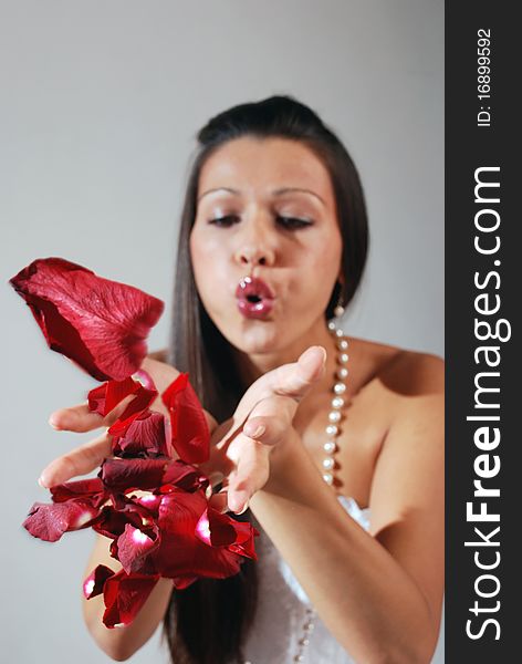 Girl blowing red petals from her hands