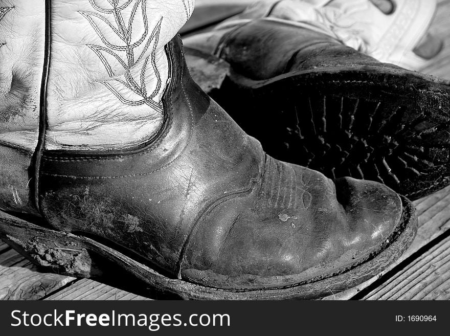 Old pair of muddy cowboy boots on rustic background. Old pair of muddy cowboy boots on rustic background