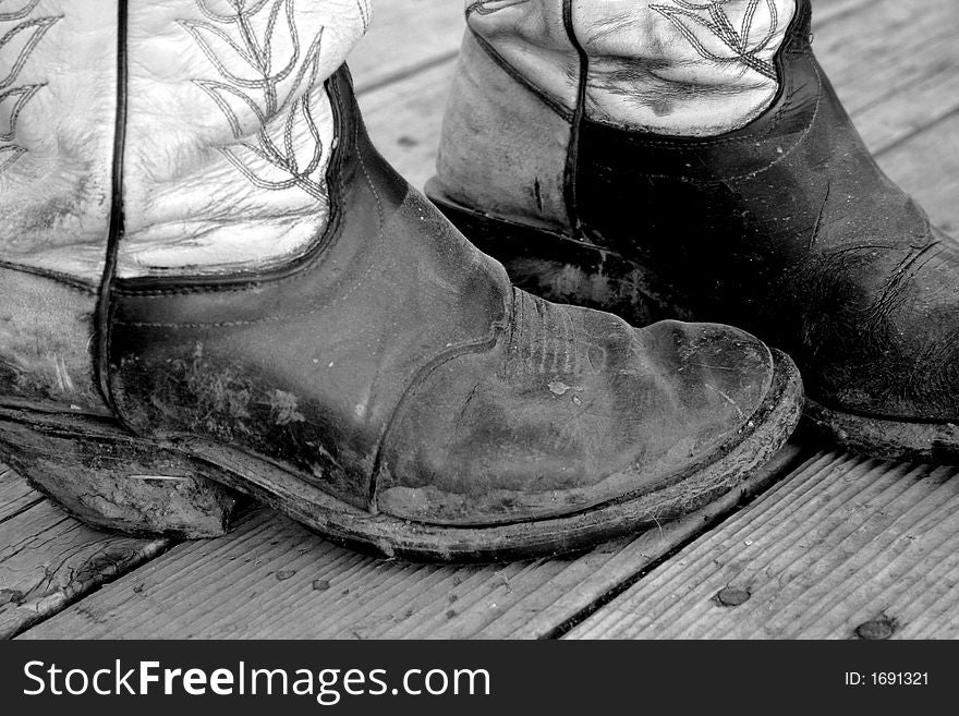 Old pair of muddy cowboy boots on rustic background. Old pair of muddy cowboy boots on rustic background