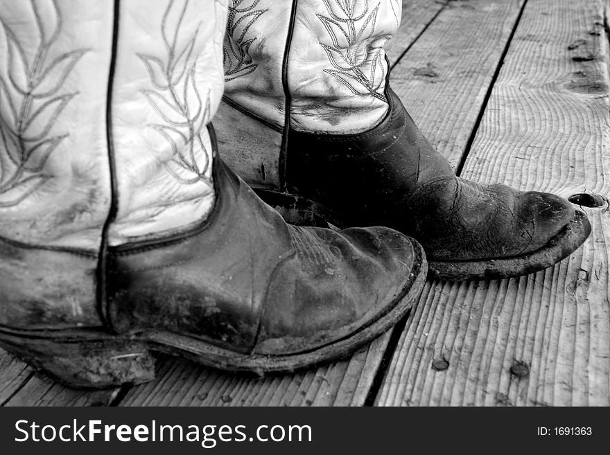 Old pair of muddy cowboy boots on rustic background. Old pair of muddy cowboy boots on rustic background