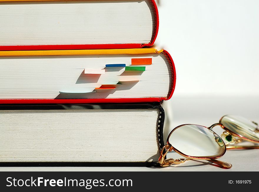 Three books and a pair of glasses. Three books and a pair of glasses