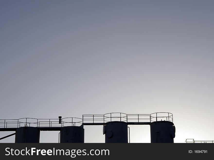 Four Tops Of Industrial Silos / Tanks As Silhouette. Four Tops Of Industrial Silos / Tanks As Silhouette