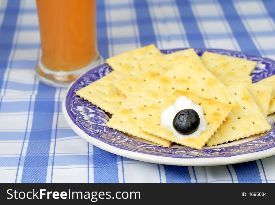 Plate with crackers,yogurt,blueberry and a glass of orange juice-good choice for a healthy breakfast.