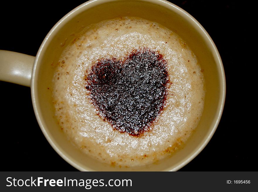 A Cup full of coffee and frothy milk with heart shaped cocoa sprinkling topping it off. A Cup full of coffee and frothy milk with heart shaped cocoa sprinkling topping it off
