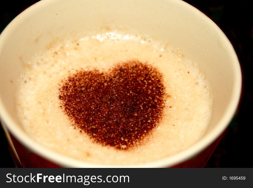 A Cup full of coffee with frothy milk and topped of with heart shaped cocoa sprinkling. A Cup full of coffee with frothy milk and topped of with heart shaped cocoa sprinkling