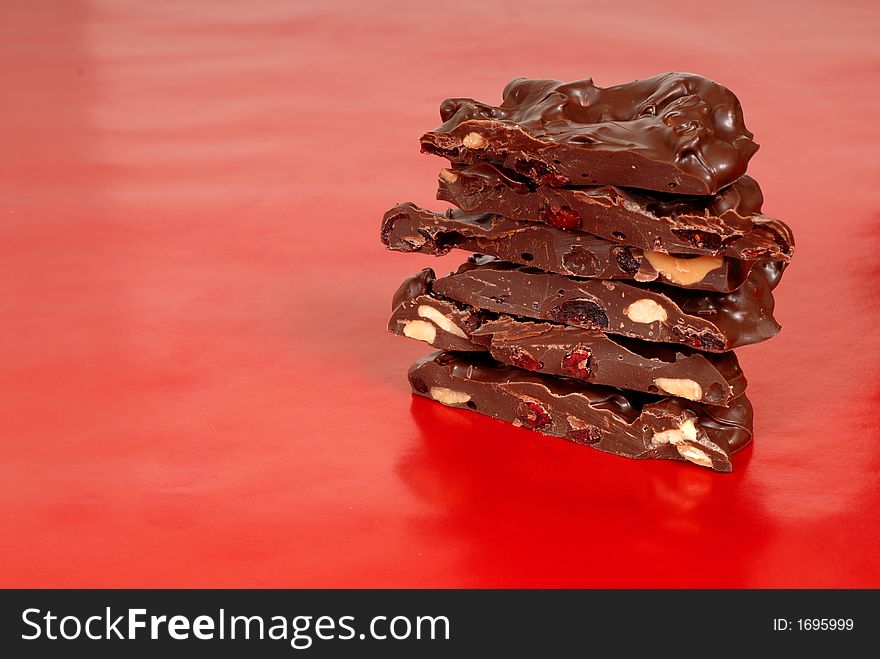 Chocolate cashew and dried cherry bark on a red background horizontal view