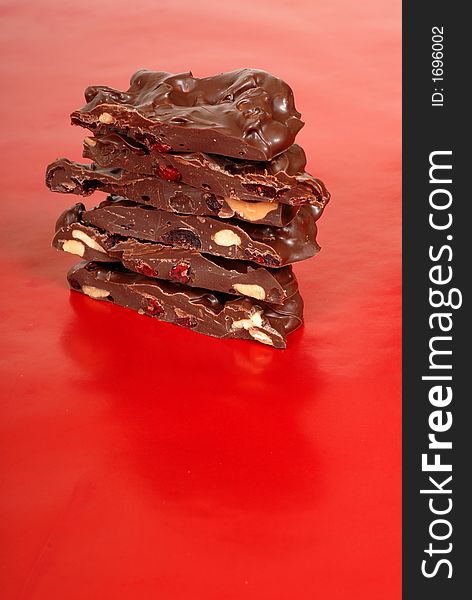 Chocolate cashew and dried cherry bark on a red background vertical view