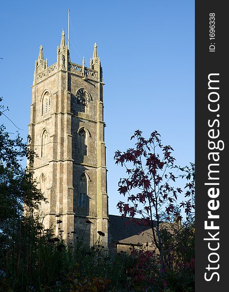 Medieval Christian church tower framed by a gap in a hedge