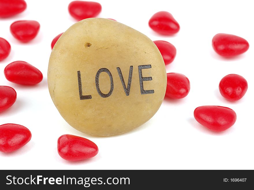Word Love carved in stone surrounded by red hearts.
