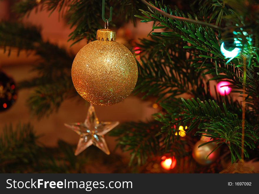 A glittery golden bauble hanging on a Christmas tree. A glittery golden bauble hanging on a Christmas tree.
