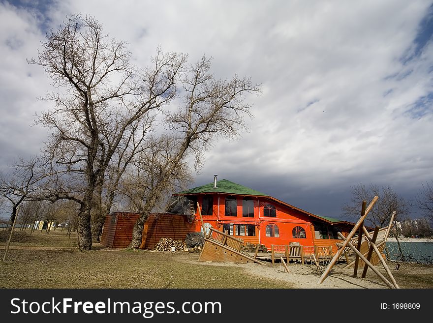 House near lake with tree and stormy clouds