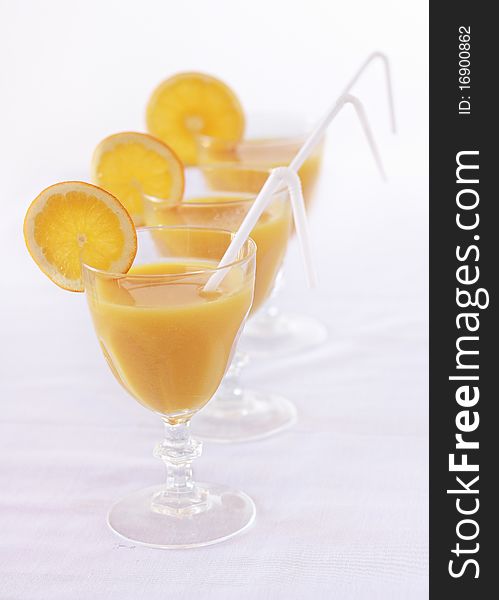 Three orange juice with slice of orange