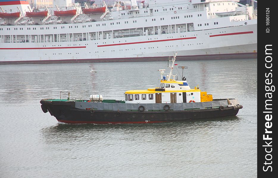 Boat with a yellow roof in the Japanese sea against the white ship