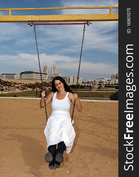 Beautiful lady with white dress on a children play device. Beautiful lady with white dress on a children play device