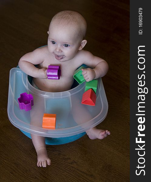 Top down view of baby sitting in chair with tray and playing with blocks. Top down view of baby sitting in chair with tray and playing with blocks.