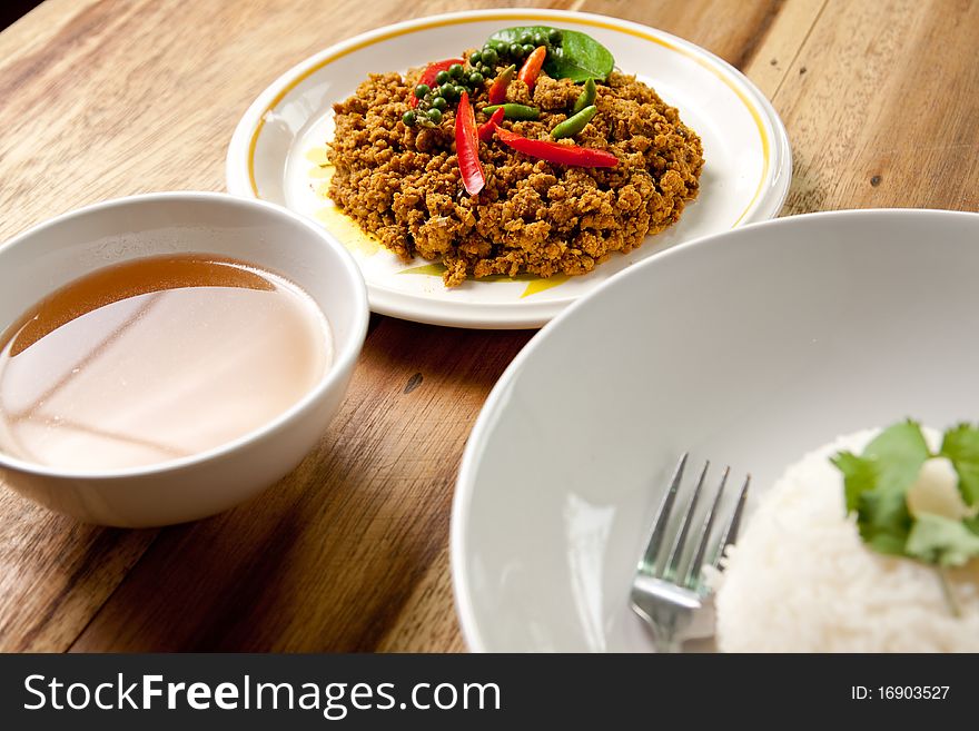 Spicy pork basil with rice and soup on wood background,thai food. Spicy pork basil with rice and soup on wood background,thai food.