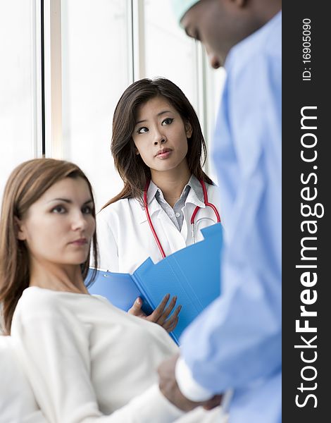 Doctor and surgeon speaking with a female patient. Doctor and surgeon speaking with a female patient