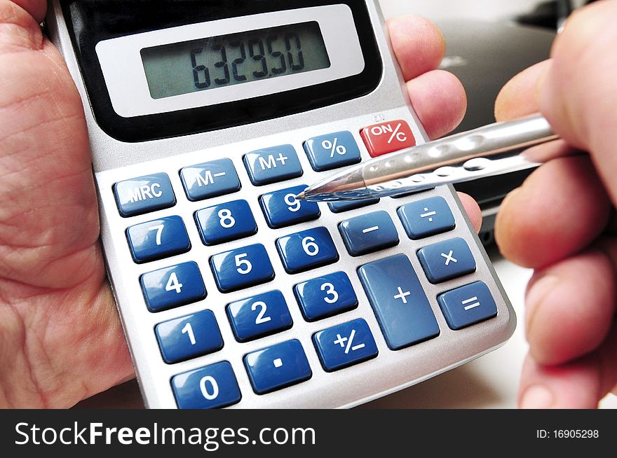 Calculator and ball point in hands of a business man