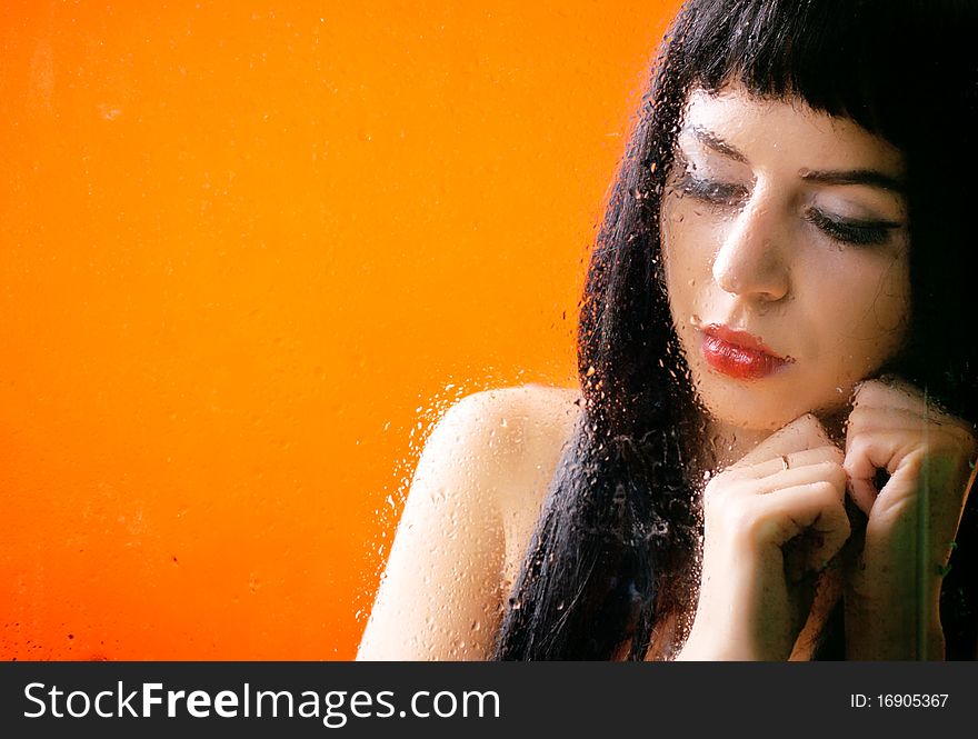 Woman behind glass with rain drops