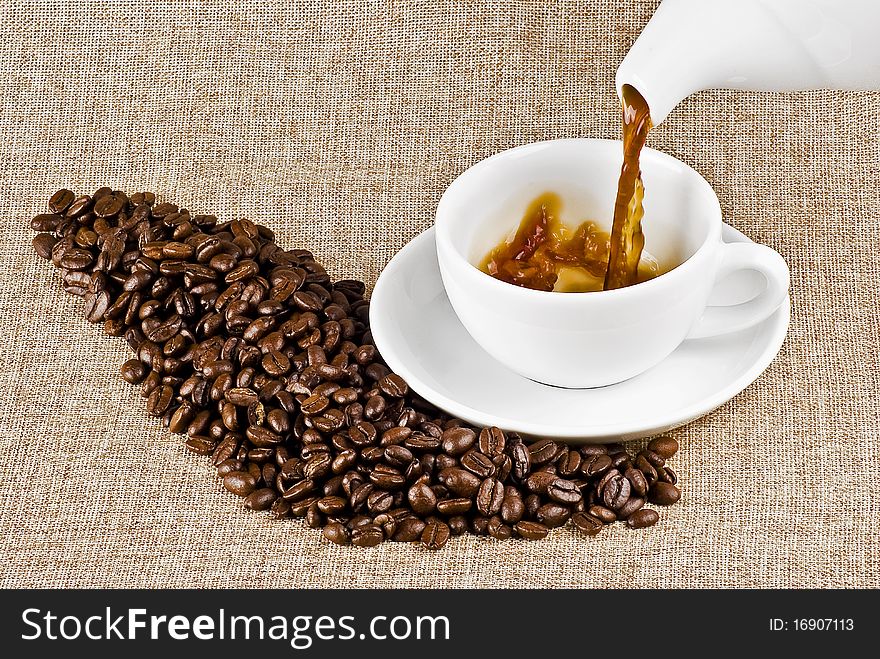 Pouring cup of coffee on burlap backround. Pouring cup of coffee on burlap backround