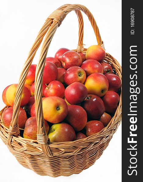 Straw basket of apples isolated on white background