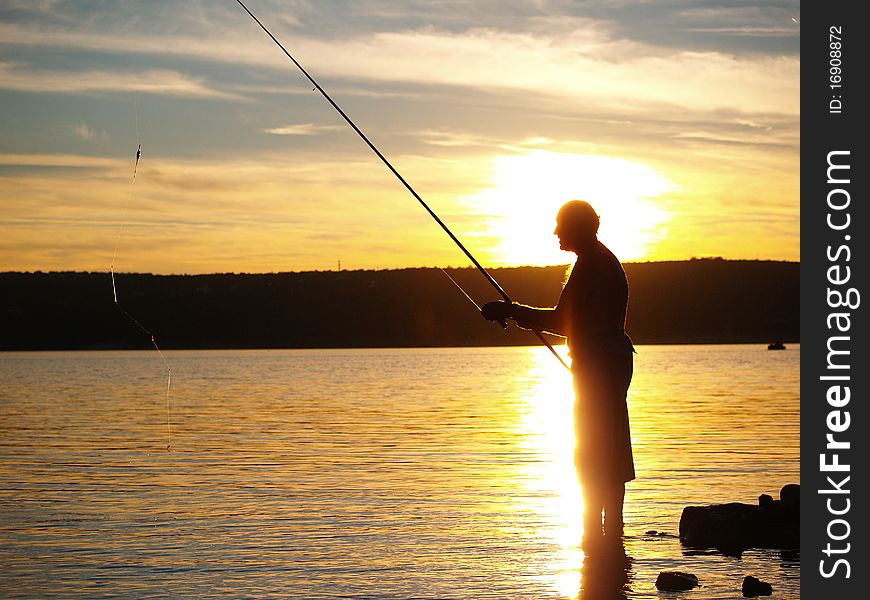 Man fishing on the coast of sea in sunset. Man fishing on the coast of sea in sunset