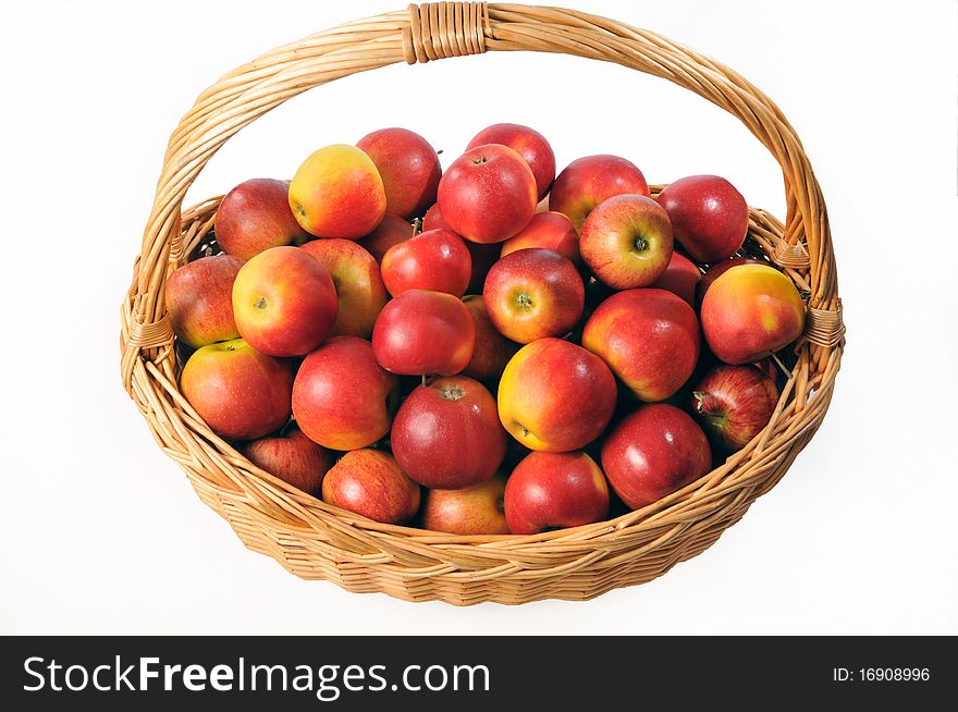 Straw basket of apples isolated on white background