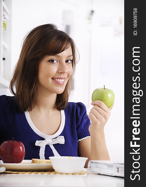 Young woman in breakfast, eating green apple, smiling and looking in camera. Young woman in breakfast, eating green apple, smiling and looking in camera