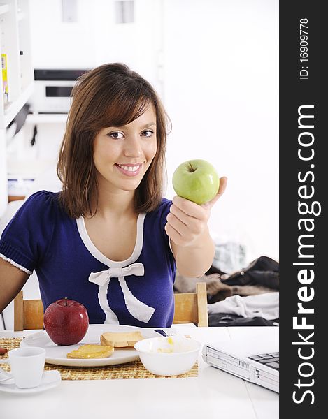 Young woman in breakfast, eating green apple, smiling and looking in camera. Young woman in breakfast, eating green apple, smiling and looking in camera