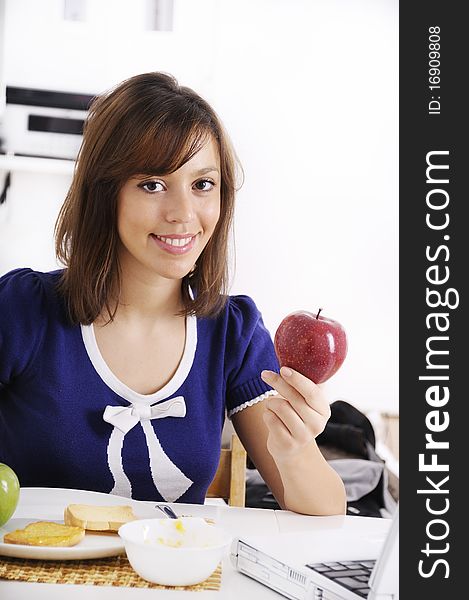 Young woman in breakfast, eating red apple, smiling and looking in camera. Young woman in breakfast, eating red apple, smiling and looking in camera
