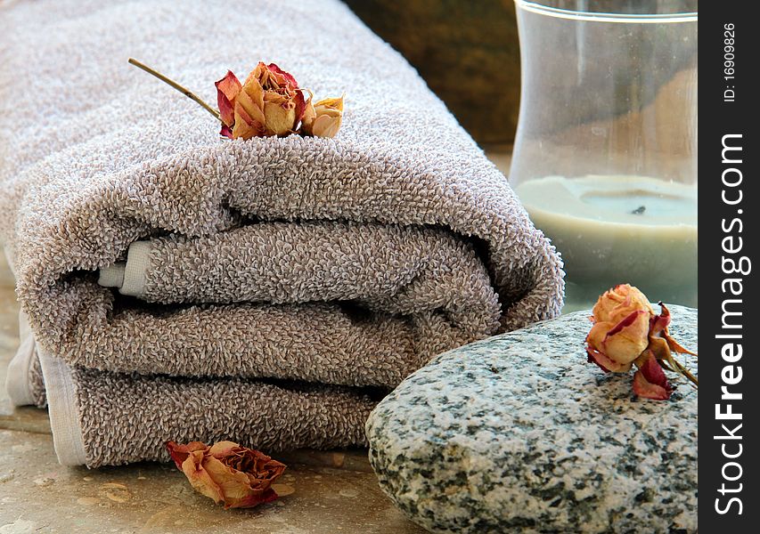 Gray towel with a rock and a candle and dry roses