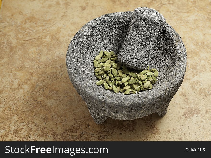Cardamom seeds green in a stone mortar and pedestal. Cardamom seeds green in a stone mortar and pedestal.