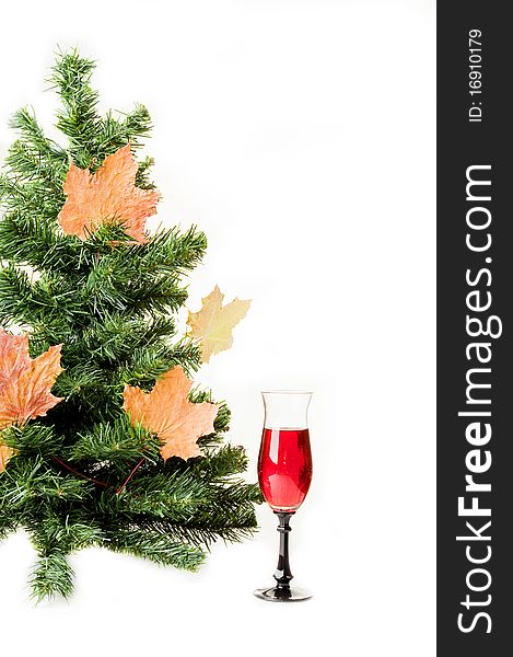 Christmas fur-tree on a white background decorated with autumn maple leaves and a wine glass. Christmas fur-tree on a white background decorated with autumn maple leaves and a wine glass