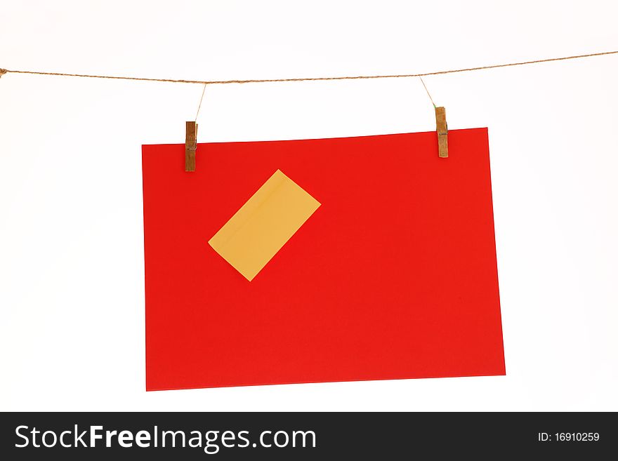 Red paper sheet and yellow on a clothes line. Isolated on white background.