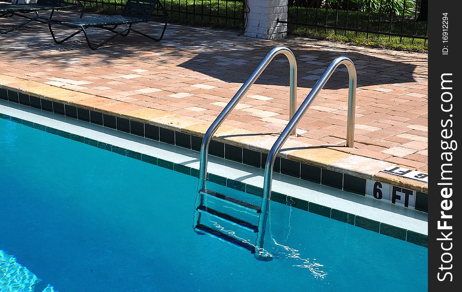 A silver metal swimming pool ladder and a brick pattern background