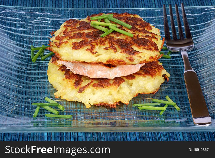 Roesti and grilled salmon with chives over a glass dish