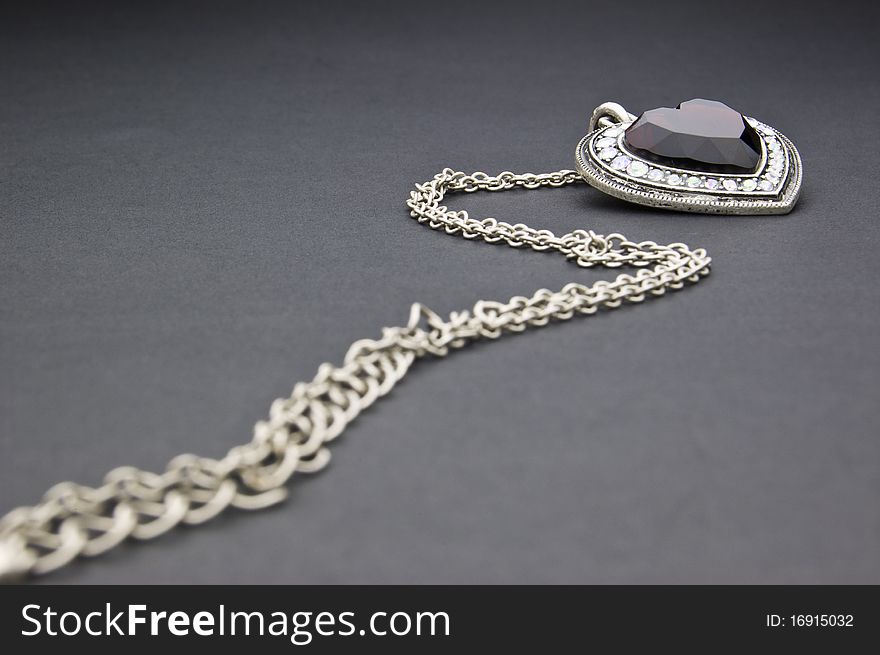 Silver necklace with heart-shaped pendant on a black background