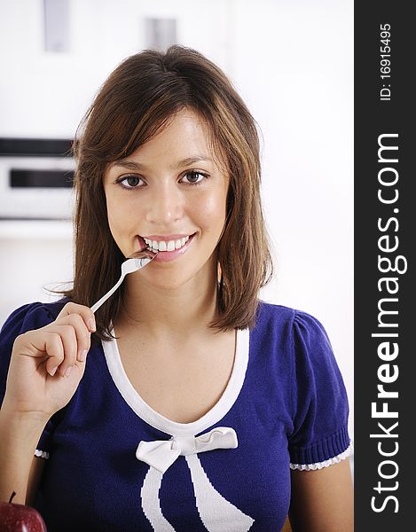 Young woman with spoon between lips smiling and looking in camera. Young woman with spoon between lips smiling and looking in camera