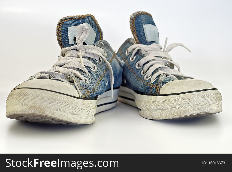 Old, dirty blue jeans sneakers over white background. Old, dirty blue jeans sneakers over white background