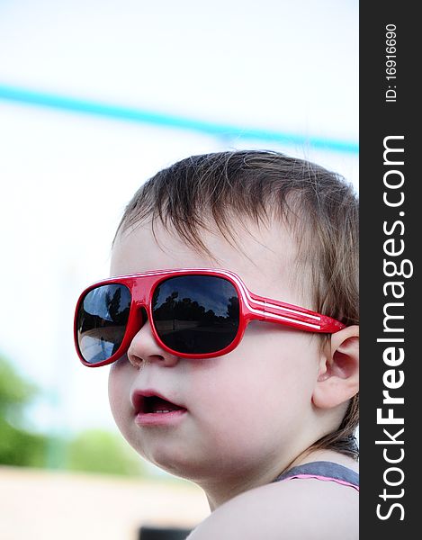 Little girl outside wearing red sunglasses. Little girl outside wearing red sunglasses