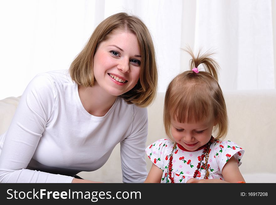 Young mother and her baby daughter spending time together. Dress up in costume jewelry.