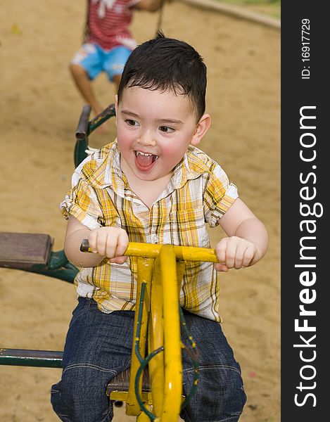 Cute boy on the playground riding on a carousel. Cute boy on the playground riding on a carousel