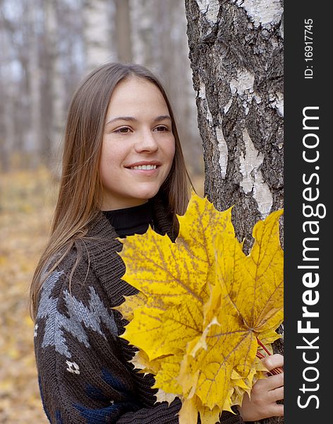 Portrait of smiling brunette girl in autumn park with leaves next to birch. Portrait of smiling brunette girl in autumn park with leaves next to birch.